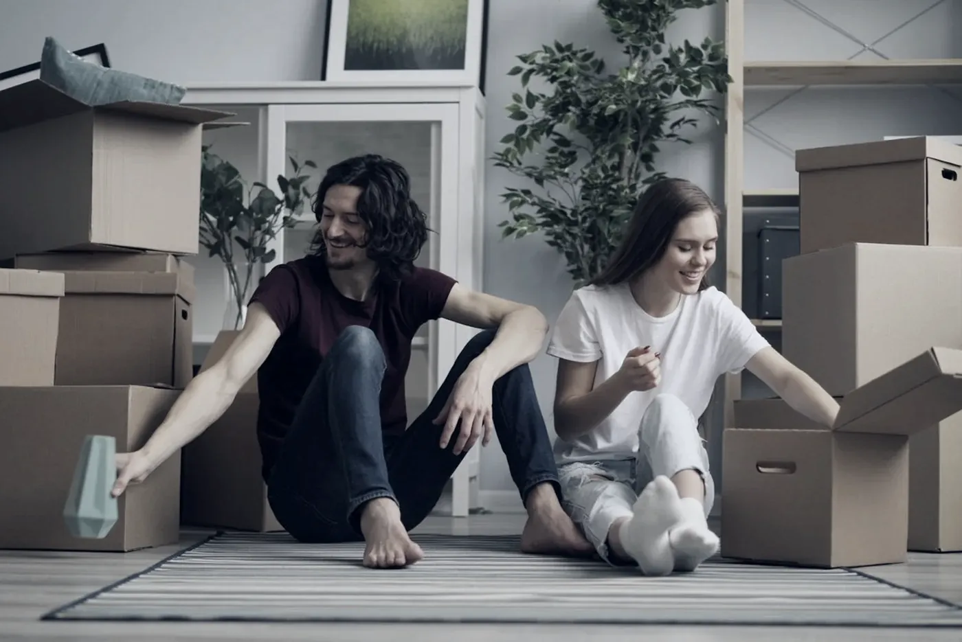 A couple sitting among moving boxes in their new home