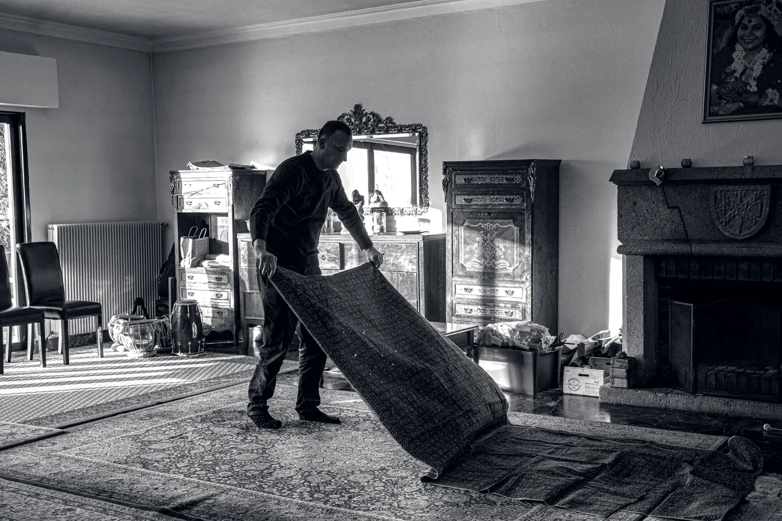 Mover laying out a rug in a furnished room